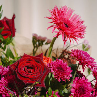Bouquet of red and pink flowers with green leaves on a neutral background