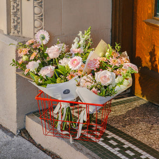 Floral arrangement in a red basket on a doorstep